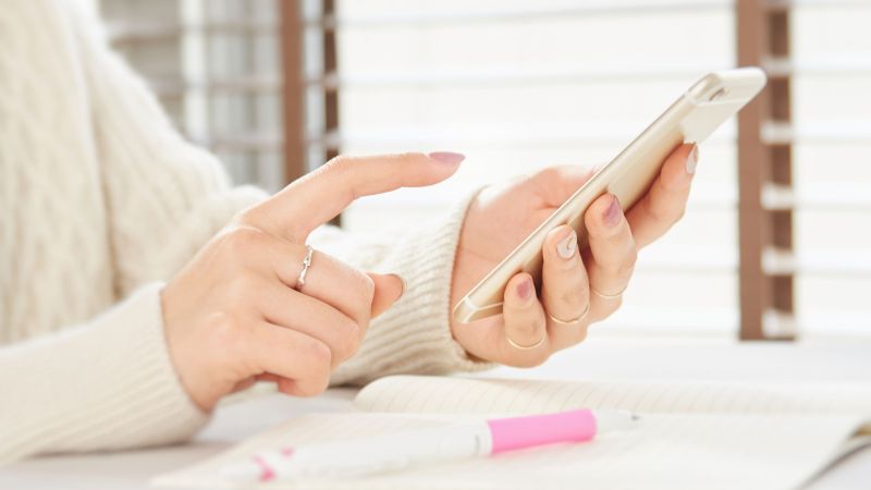 スマホで時間を確認する女性